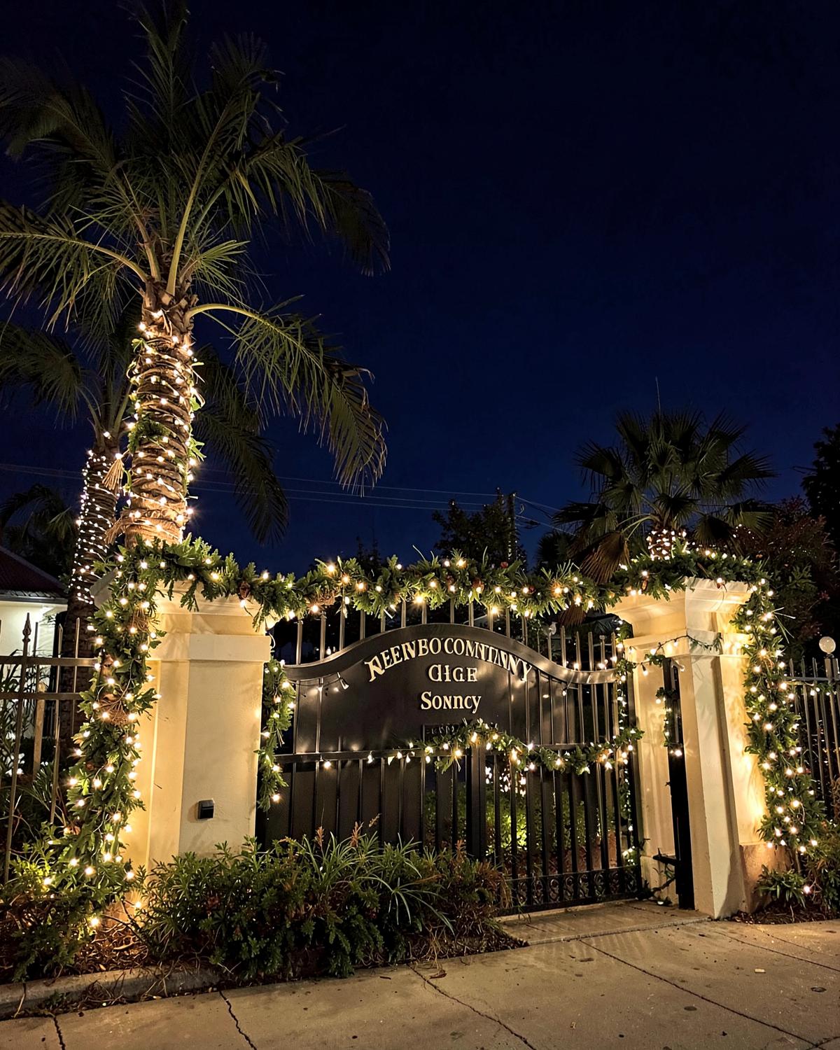 Neighborhood entrance sign with garland and lights in Miramar Beach
